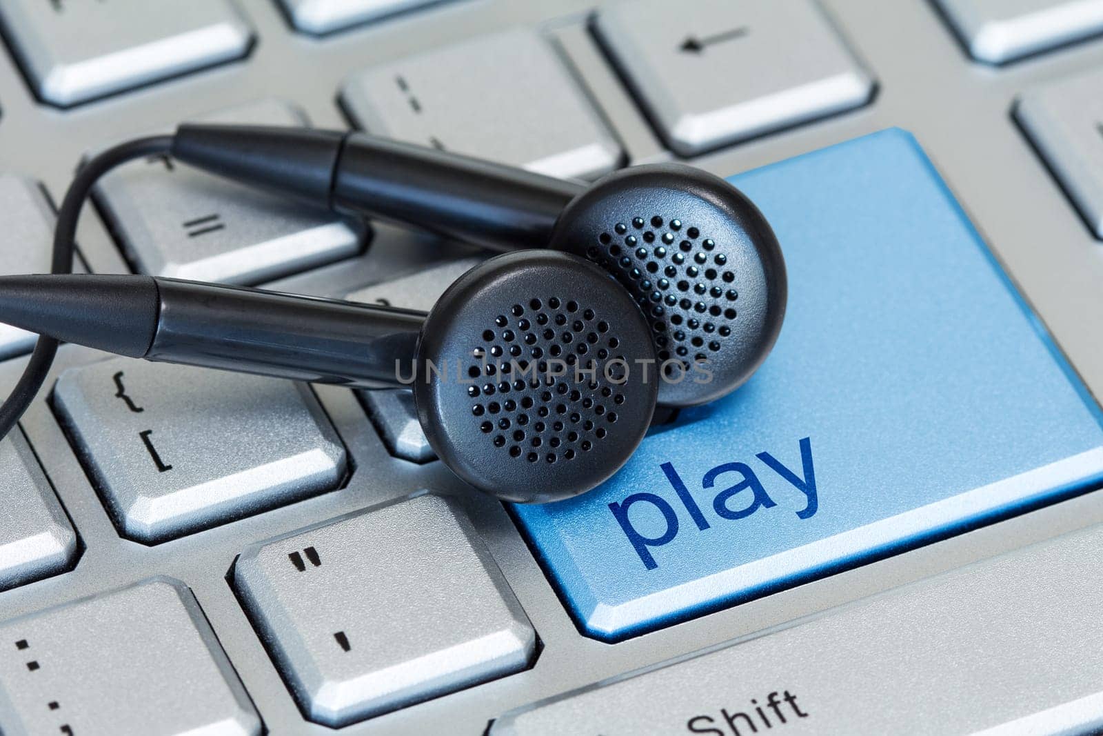 Earphones on computer keyboard with a play button