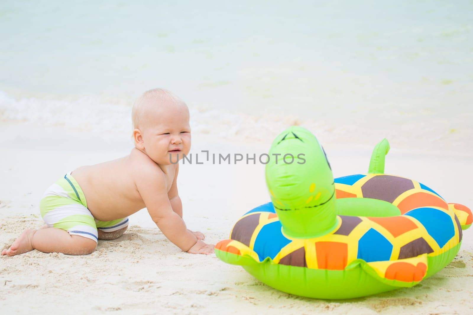 Baby sitting om the beach with swim ring
