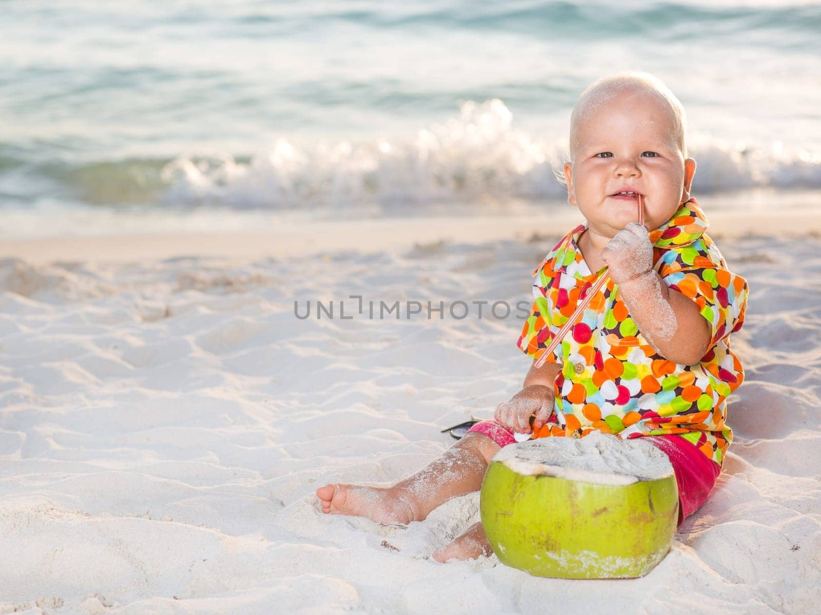 Funny baby with coconut on the beach