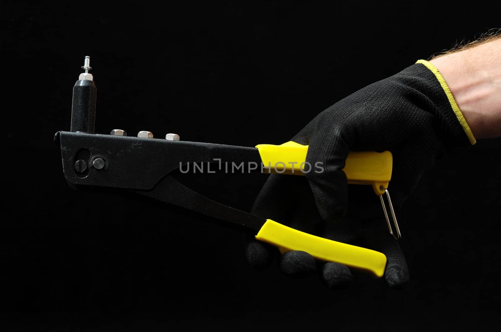 Rivets Pliers and a Hand on a Black Background