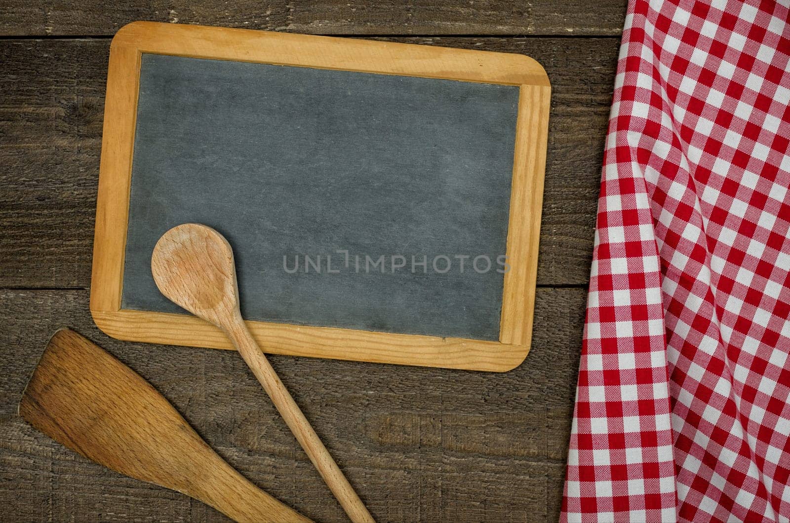 Empty slate table with cooking spoons and red plaid tablecloth