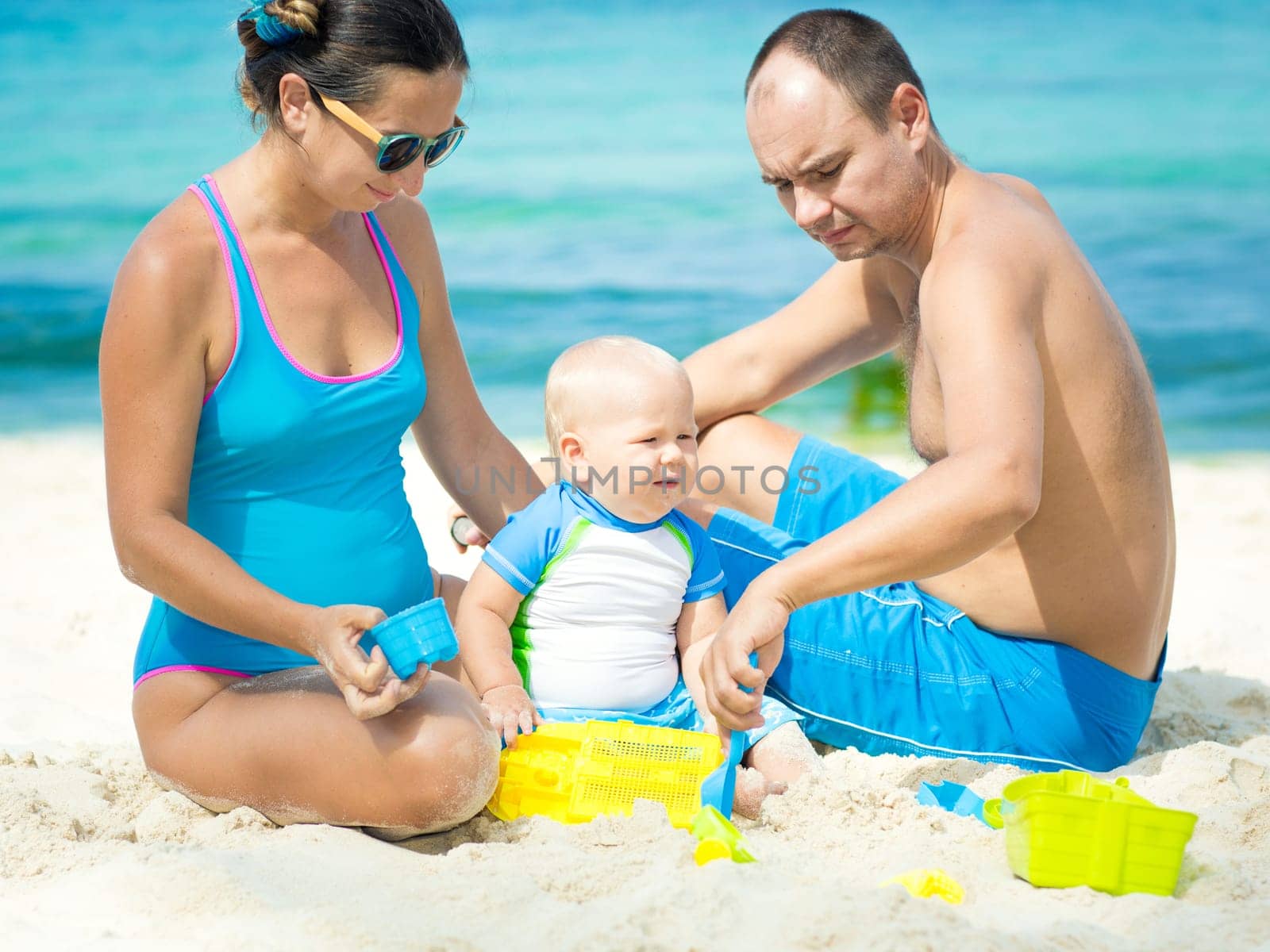 Parents and baby playing together on the beach