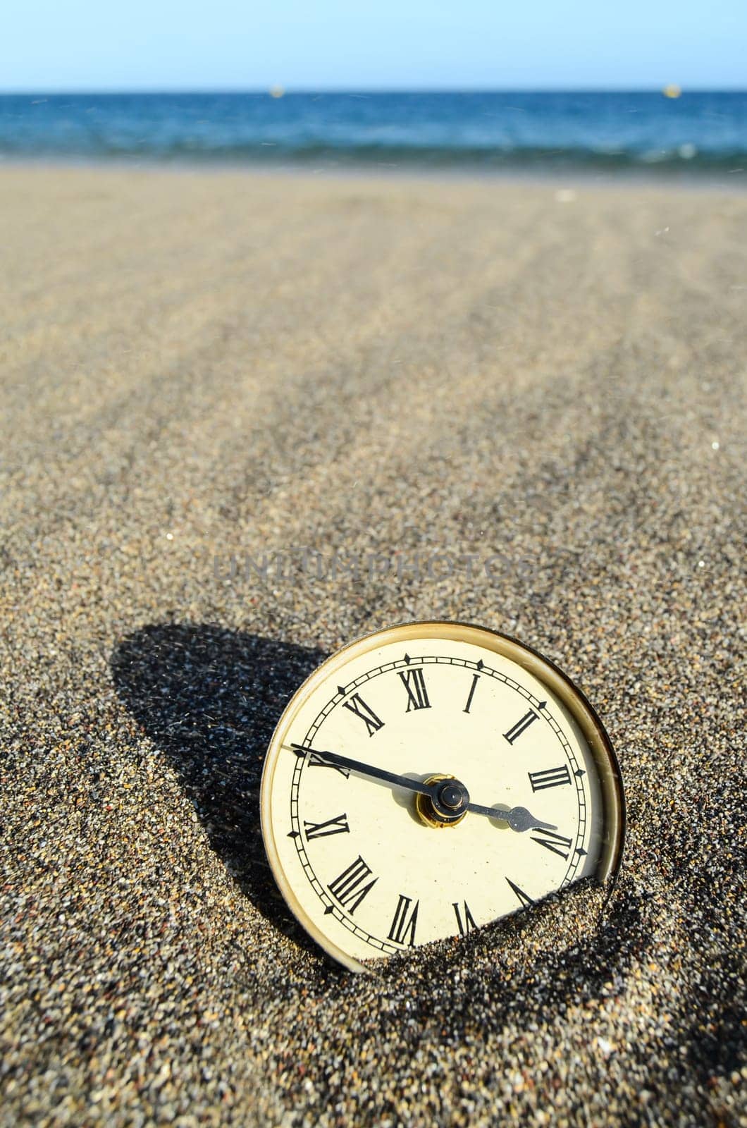 Classic Analog Clock In The Sand On The Beach Near The Ocean