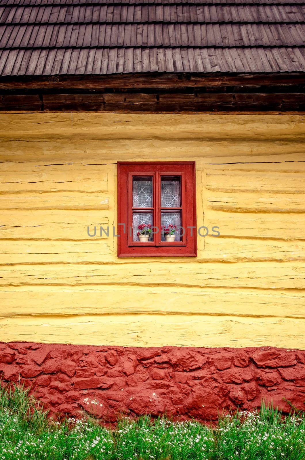 Detail of colorful window with flowers on old traditional wooden house