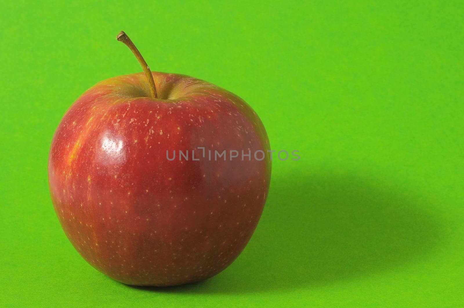 One Juicy Hot Red Apple over a Colored Background
