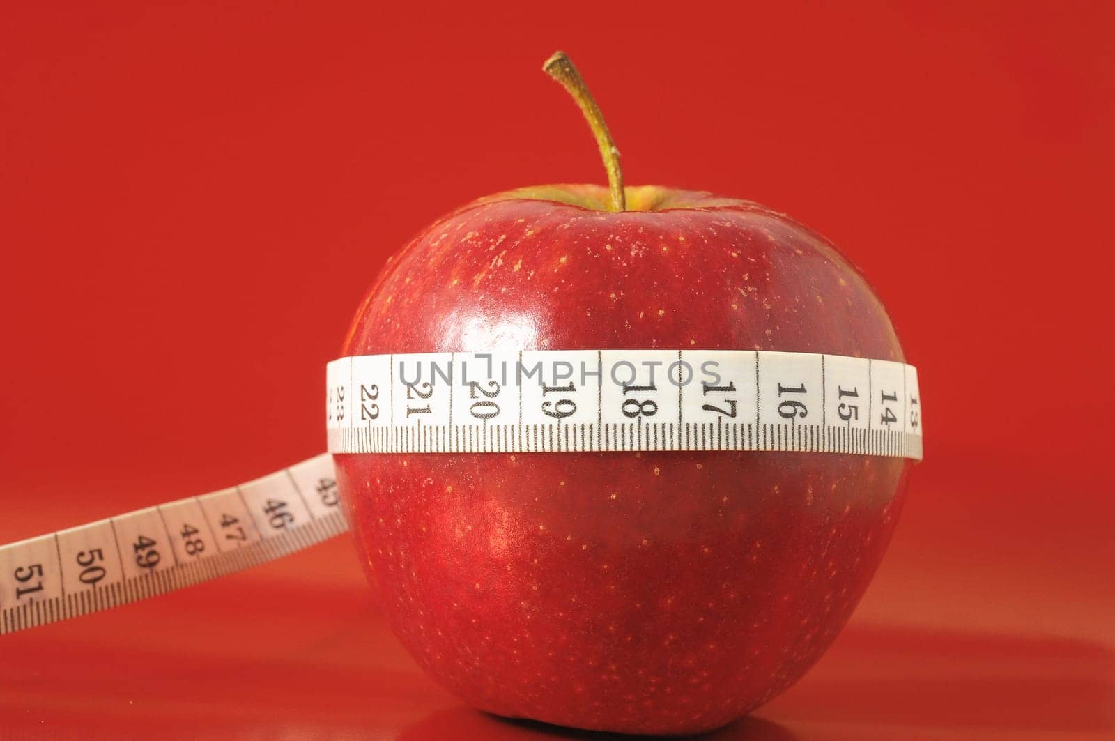 Measuring Tape Wrapped Around a Red Apple as a Symbol of Diet