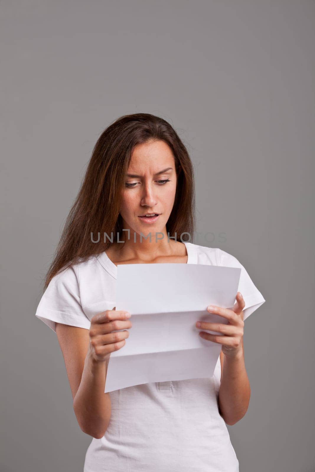 brunette young woman realizes that something wrong happened reading a white letter or document