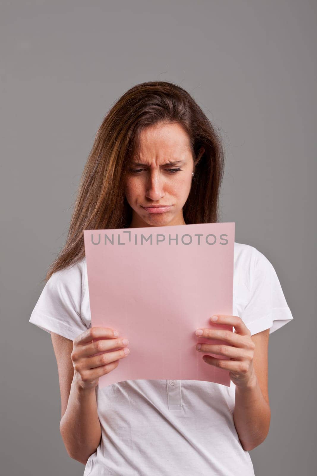 girl pouts because she read something bad on a pink document maybe by a lover or a money loss