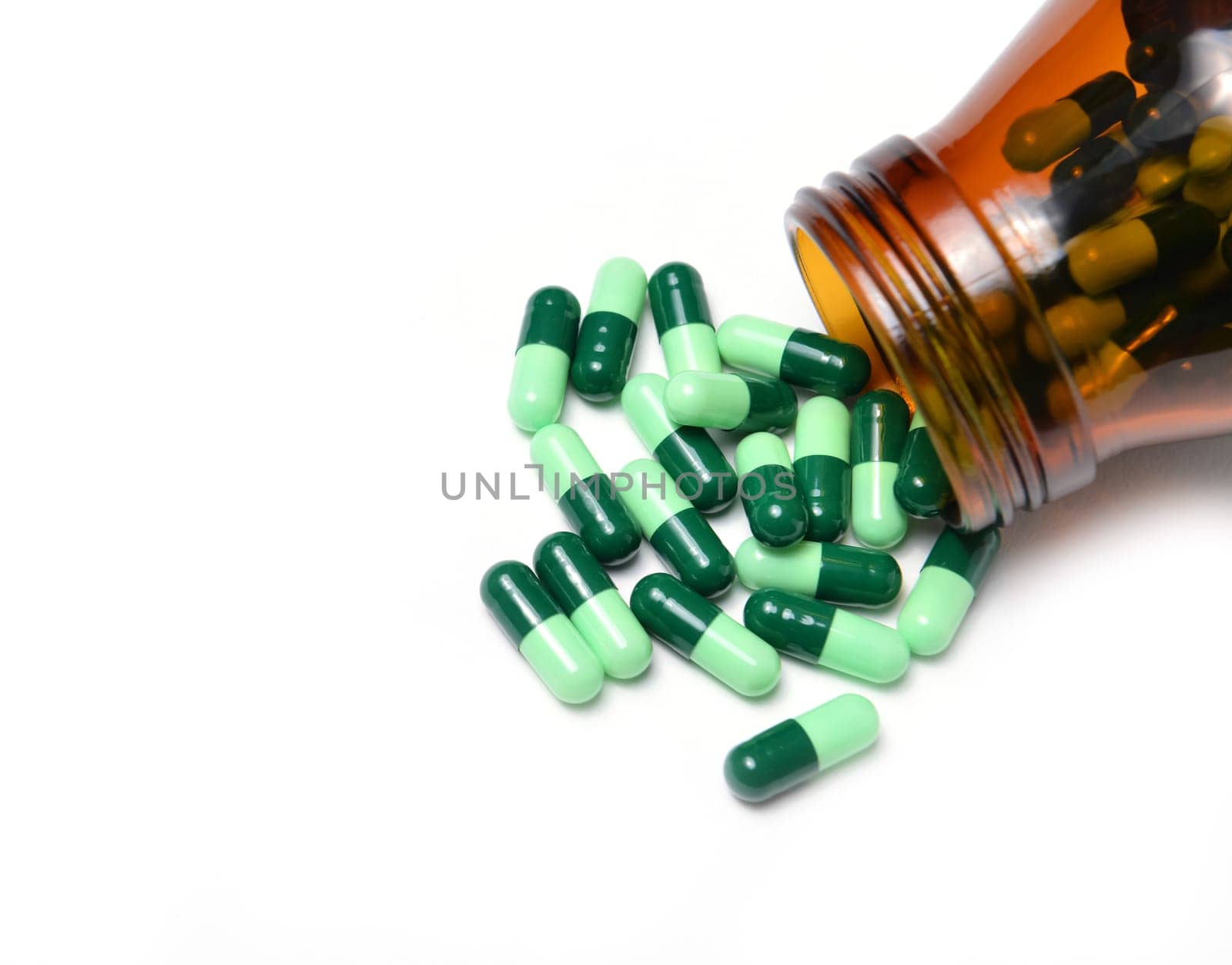 group of green capsule medicine in bottle on white background