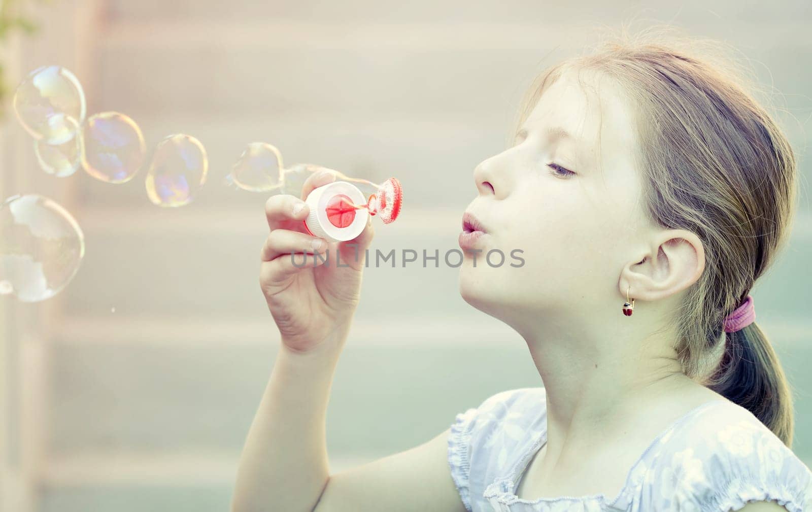 Retro styled photo of young girl blowing soap bubbles