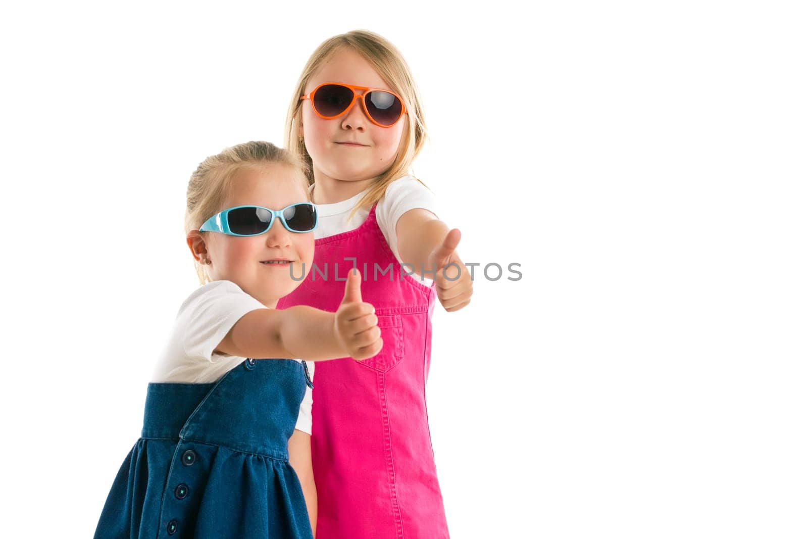 two little girls showing thumbs up. Studio shot.