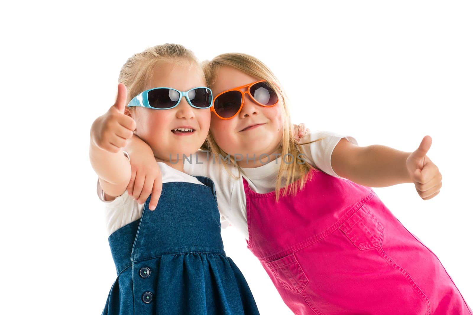 two little girls showing thumbs up. Studio shot.