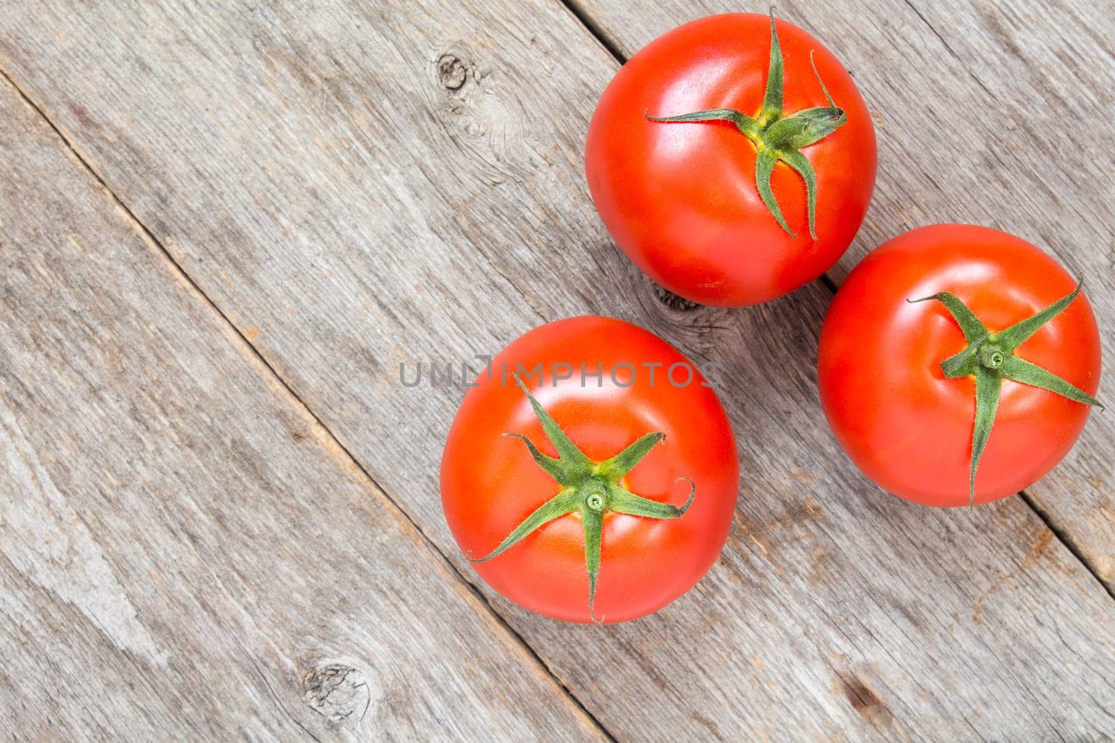 Three fresh red tomatoes on wooden background