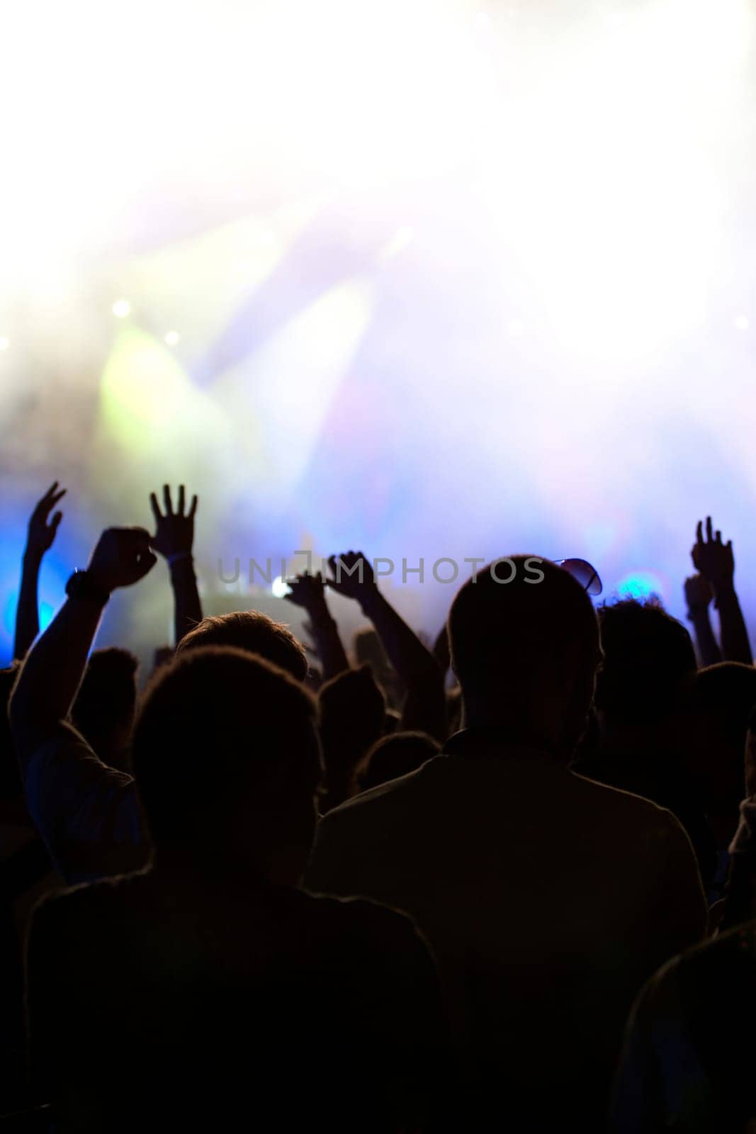Cheering crowd in front of bright colorful stage lights