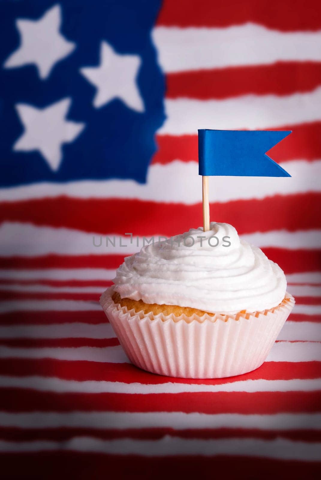 Cupcake with white Topping and Blue Flag with Copyspace for Your Text in front of an American Flag like Background