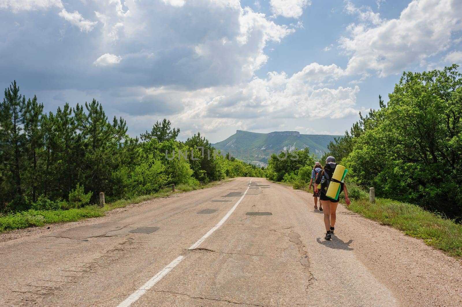 two people traveling with backpacks, walking on the road