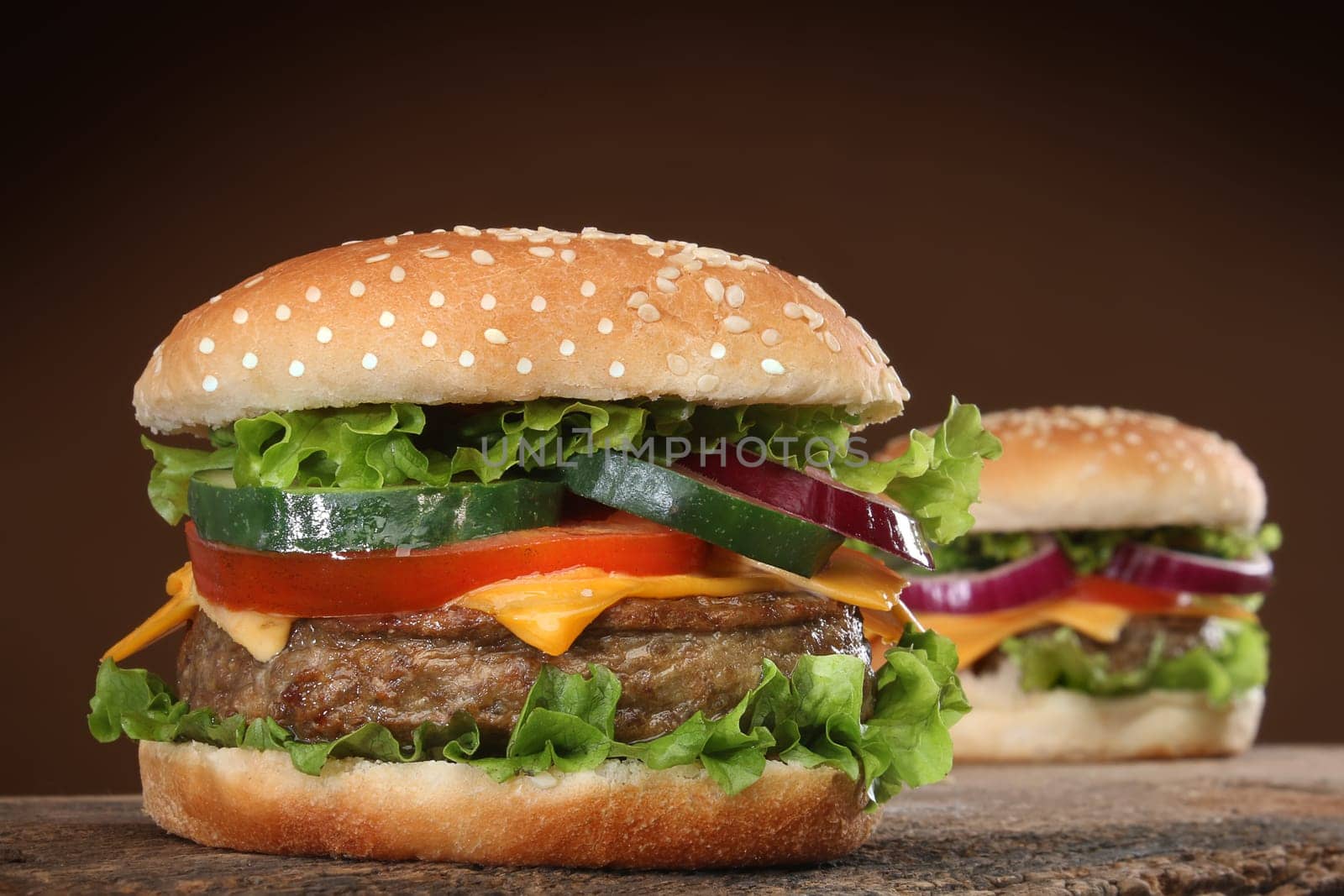Two delicious hamburgers on wood background.