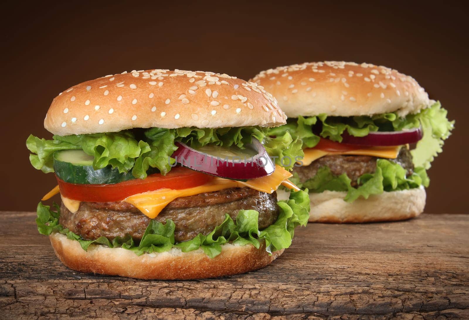 Two delicious hamburgers on wood background.
