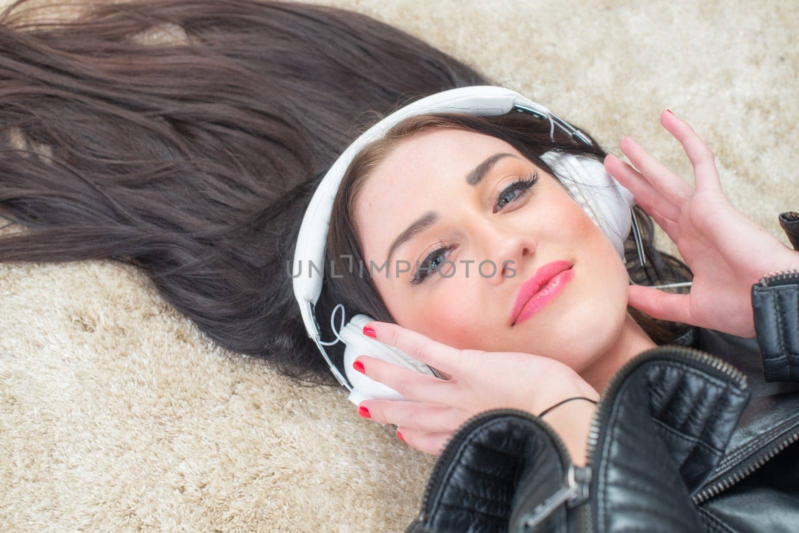 Young woman lies on the carpet listening to music