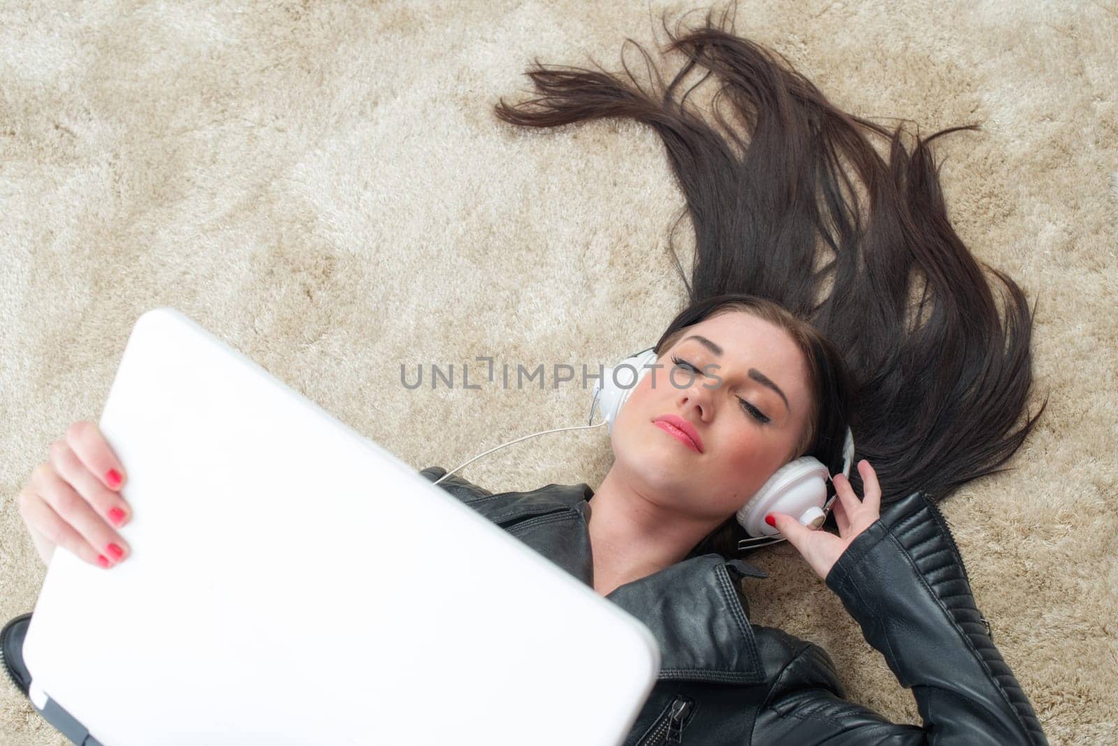 Young woman lies on the carpet listening to music