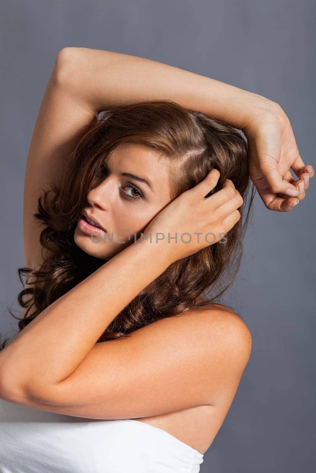 Young attractive brunette woman with curls and white top as portrait
