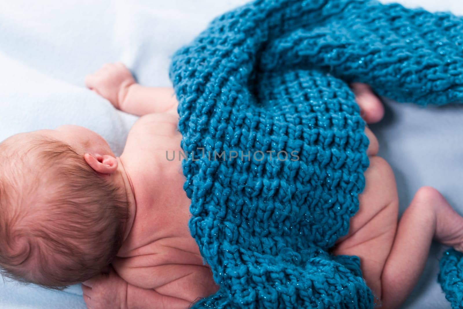 Newborn baby wrapped in a scarf sleeps naked as a close-up