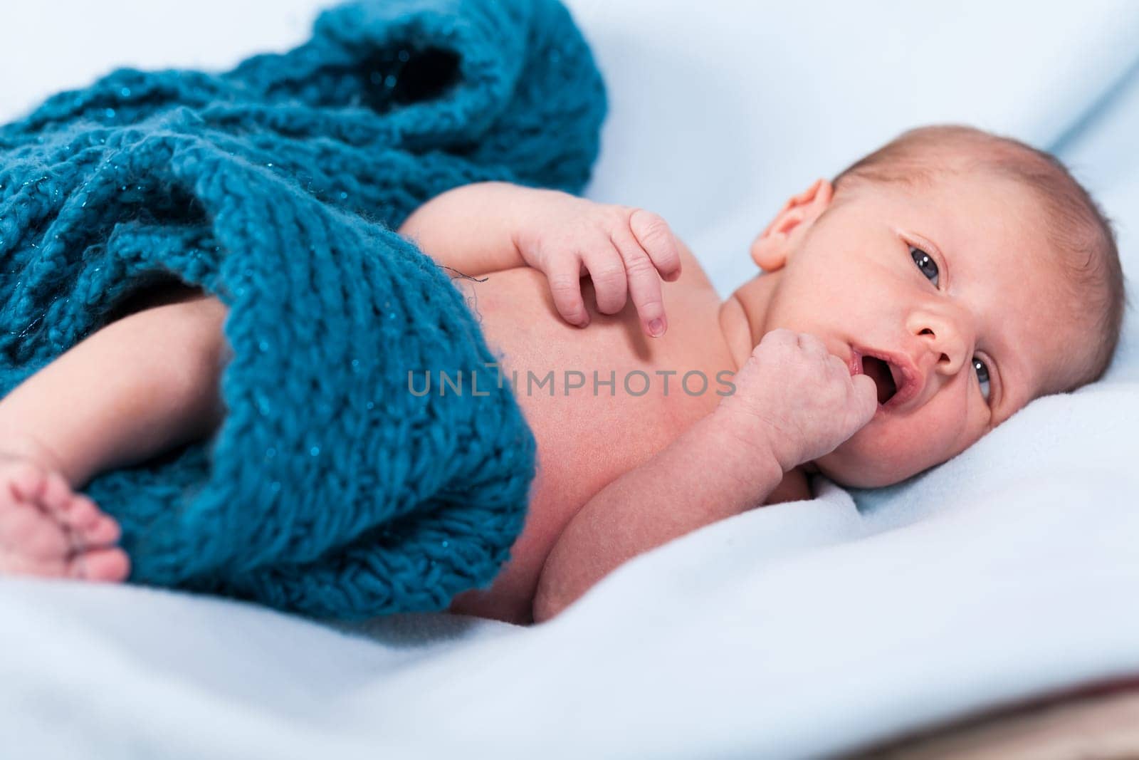 Newborn baby wrapped in a scarf sleeps naked as a close-up