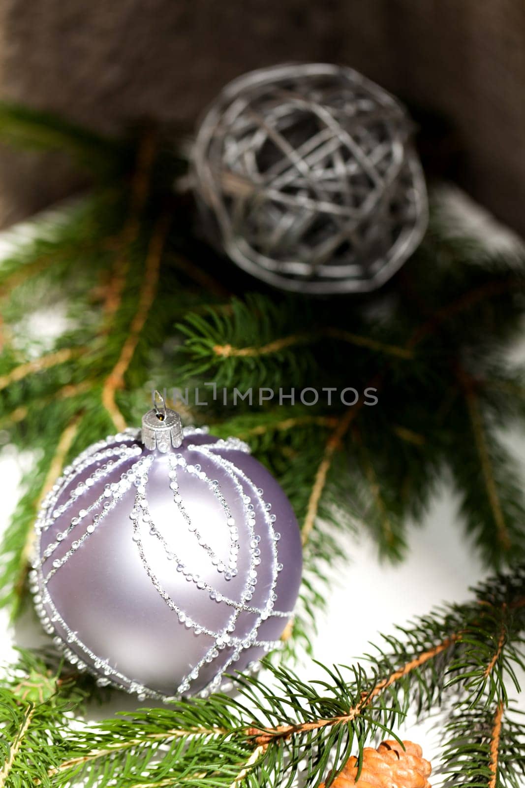 Silver Christmas tree balls in green fir branches with white shiny snow as macro detail