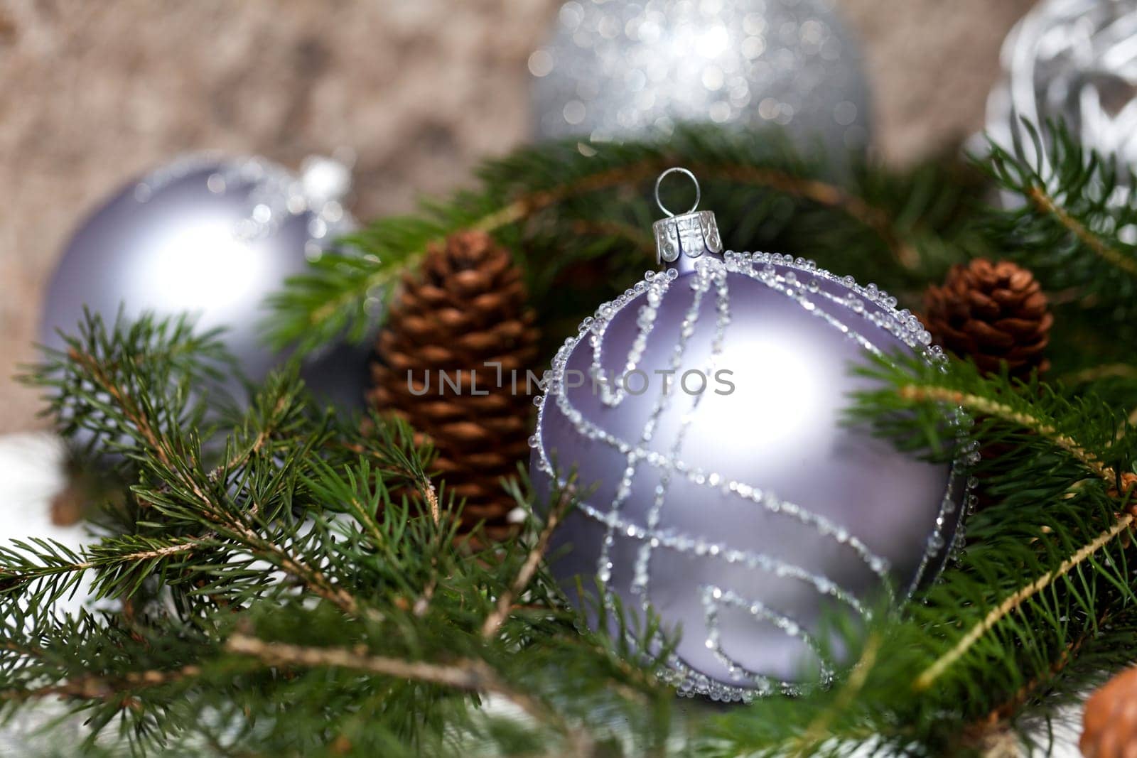 Silver Christmas tree balls in green fir branches with white shiny snow as macro detail