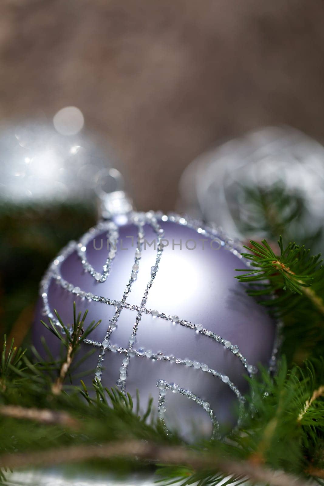 Silver Christmas tree balls in green fir branches with white shiny snow as macro detail
