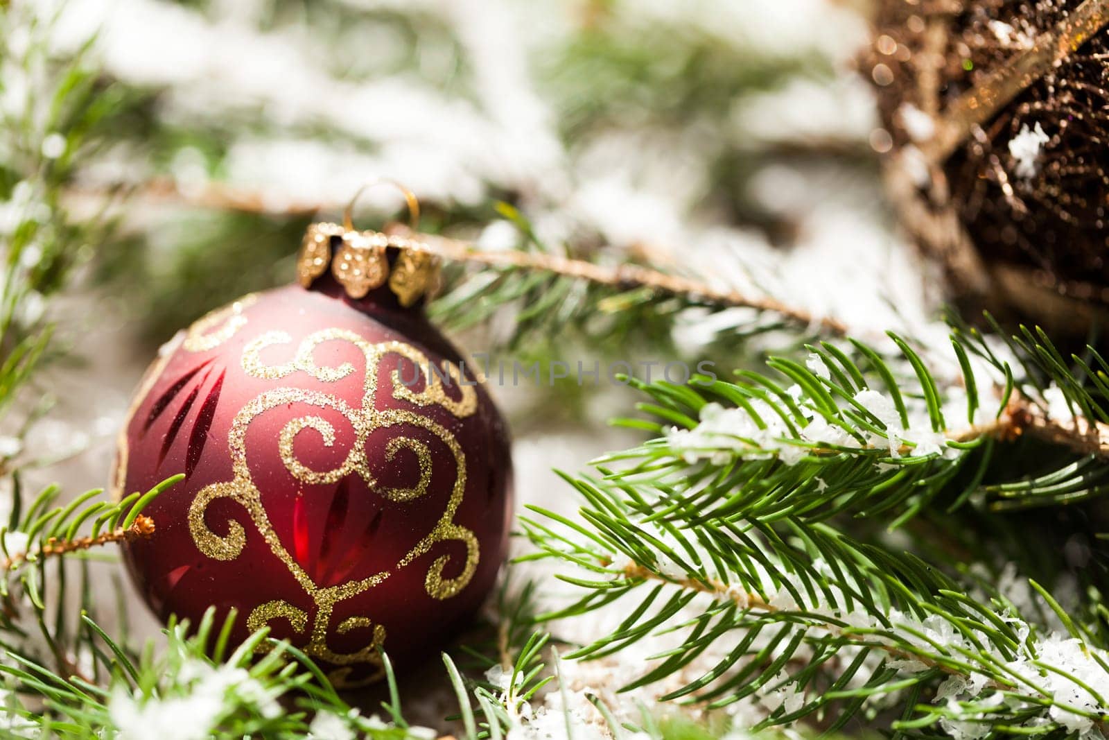 Decoration for Christmas with red and gold Christmas tree balls in front of green fir branches in the background