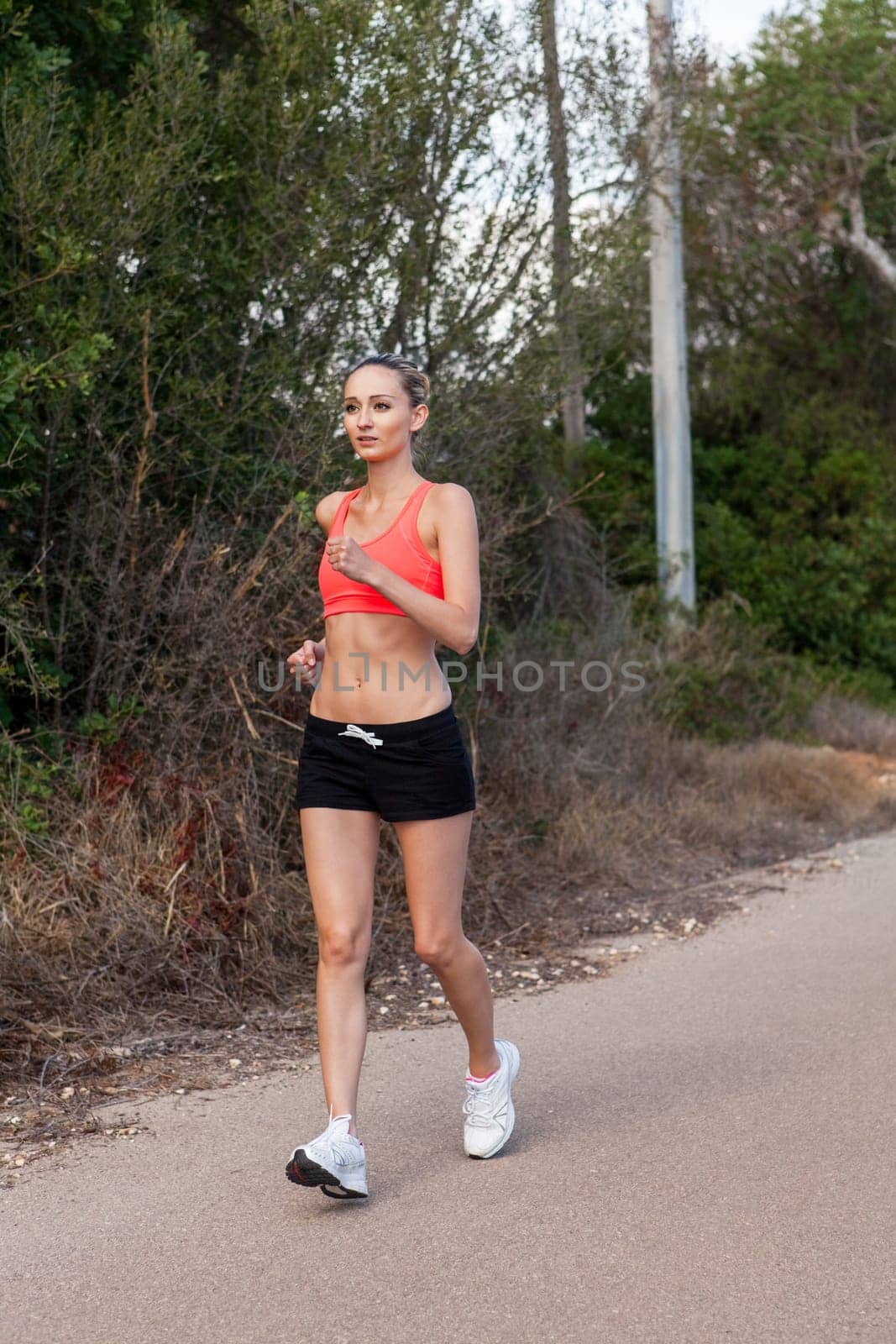 attractive sporty young woman jogging on an outdoor street in daylight