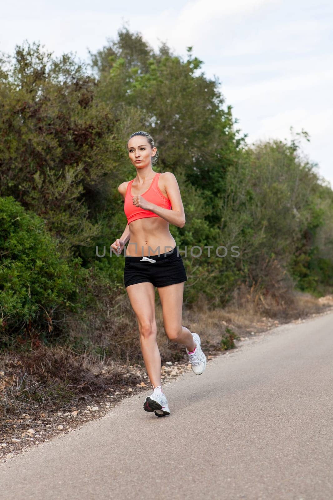 attractive sporty young woman jogging on an outdoor street in daylight