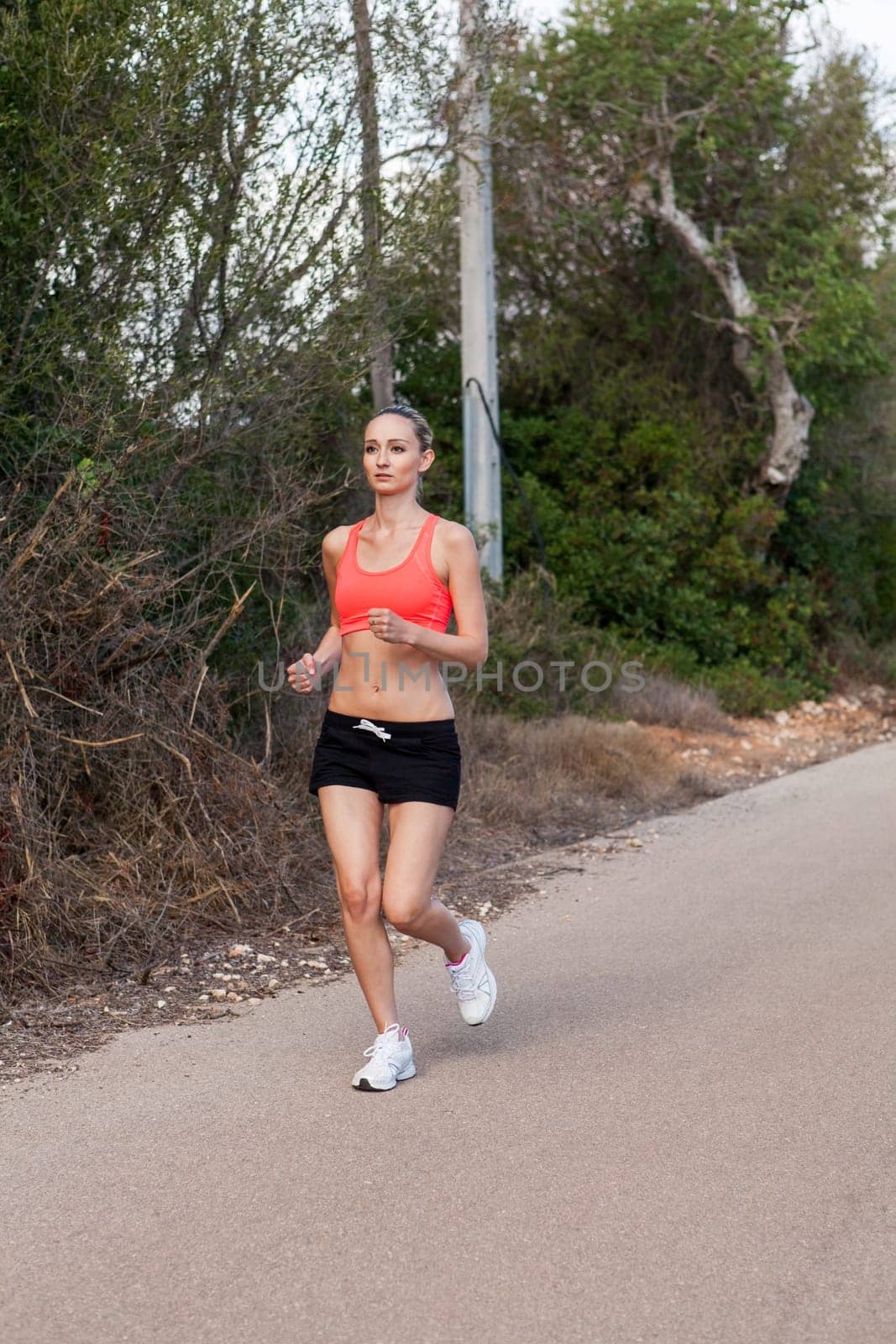 attractive sporty young woman jogging on an outdoor street in daylight