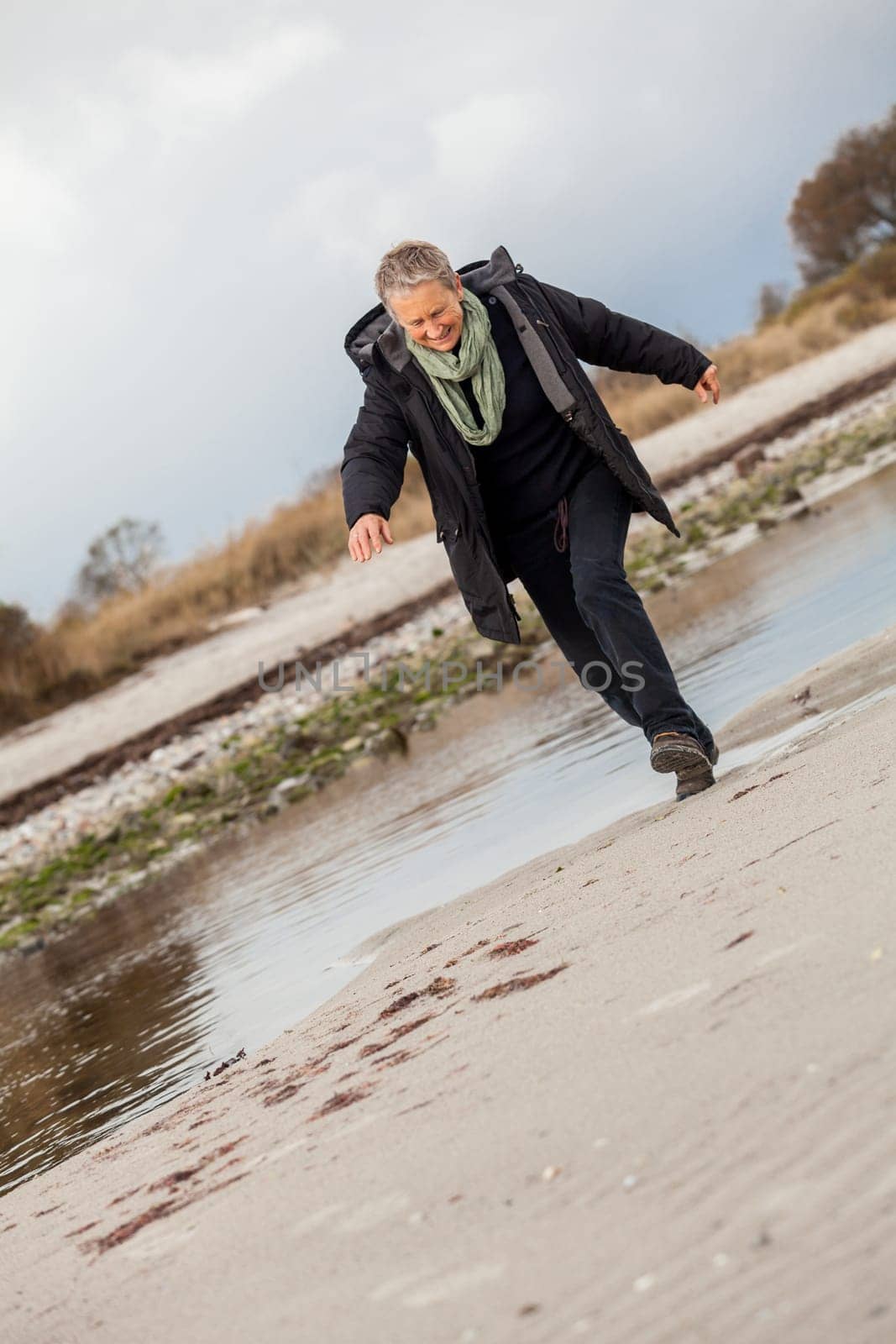 happy active older woman pensioner senior in the open at the sea in autumn