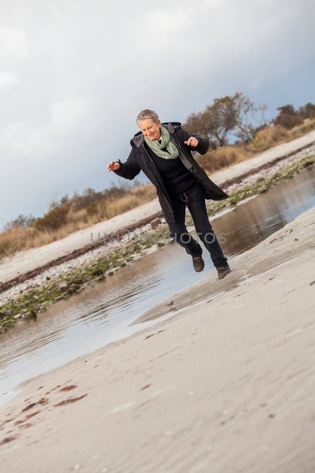 happy active older woman pensioner senior in the open at the sea in autumn