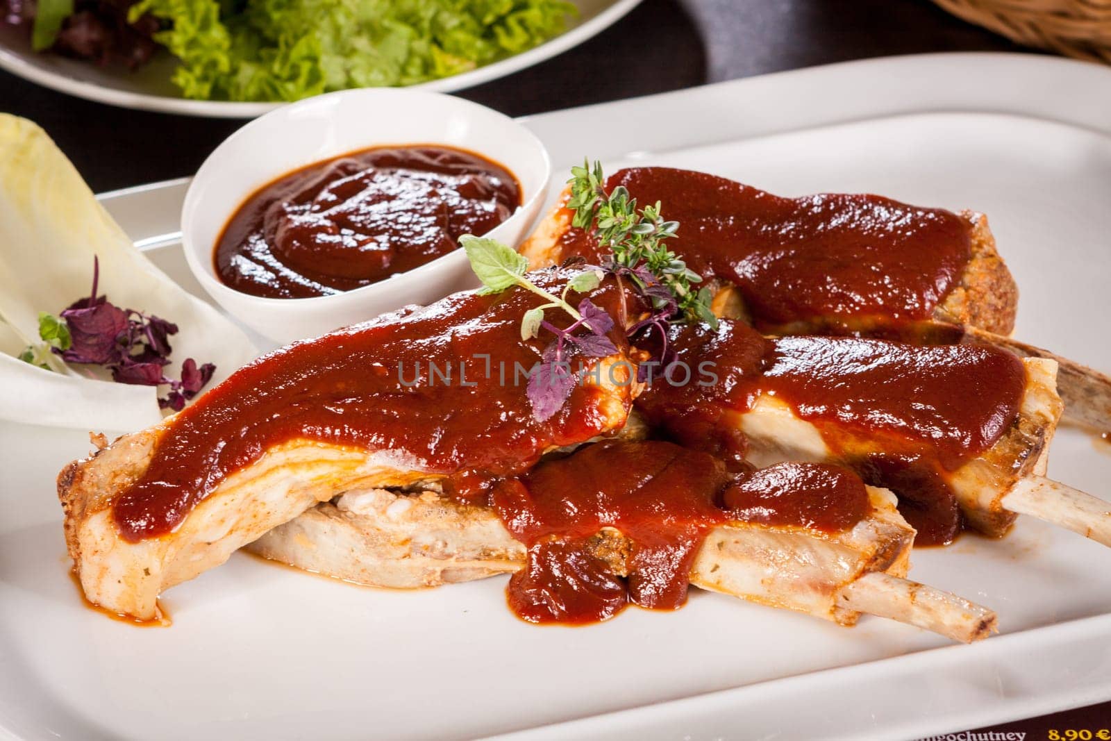 Grilled pork ribs Spareribs with barbecue sauce marinade and herb salad on a plate