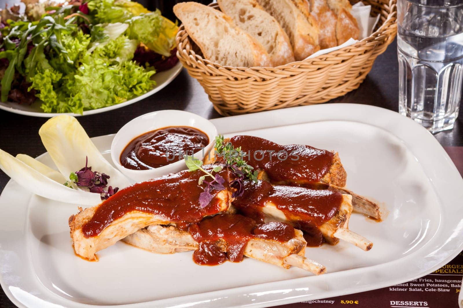 Grilled pork ribs Spareribs with barbecue sauce marinade and herb salad on a plate