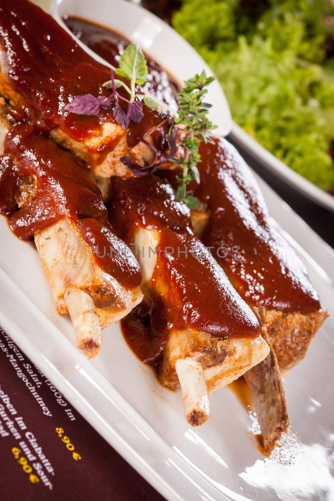 Grilled pork ribs Spareribs with barbecue sauce marinade and herb salad on a plate
