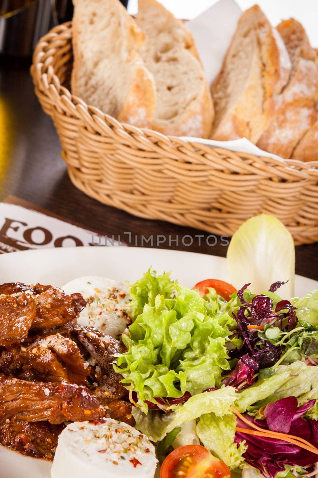 Fresh salad with fresh goat cheese and fried beef strips served on a plate