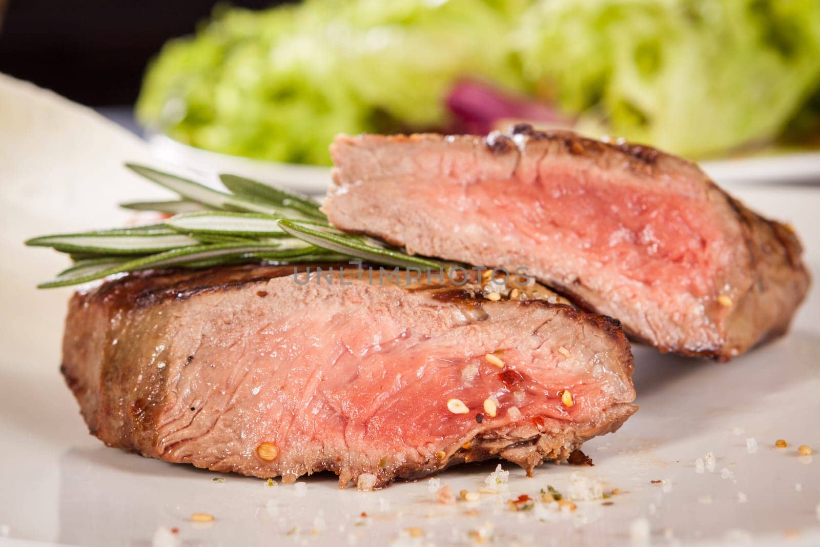 Medium fried beef steak fillet with pepper and rosemary sliced on a plate