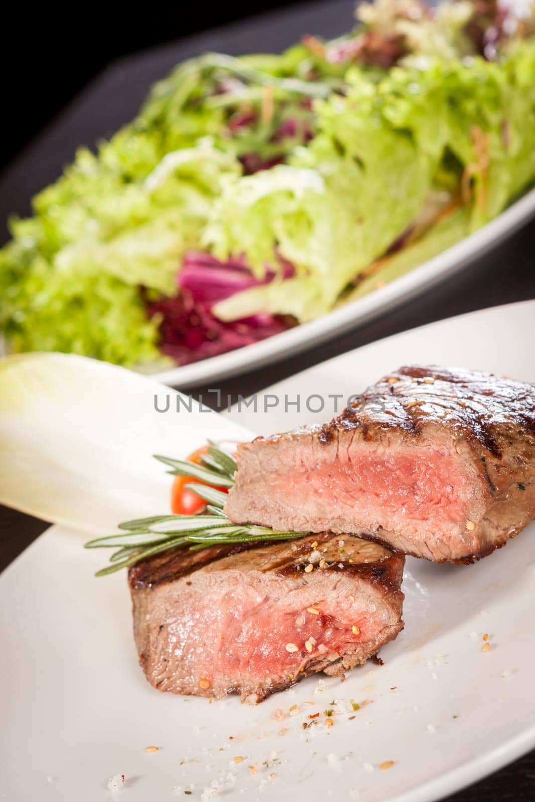 Medium fried beef steak fillet with pepper and rosemary sliced on a plate