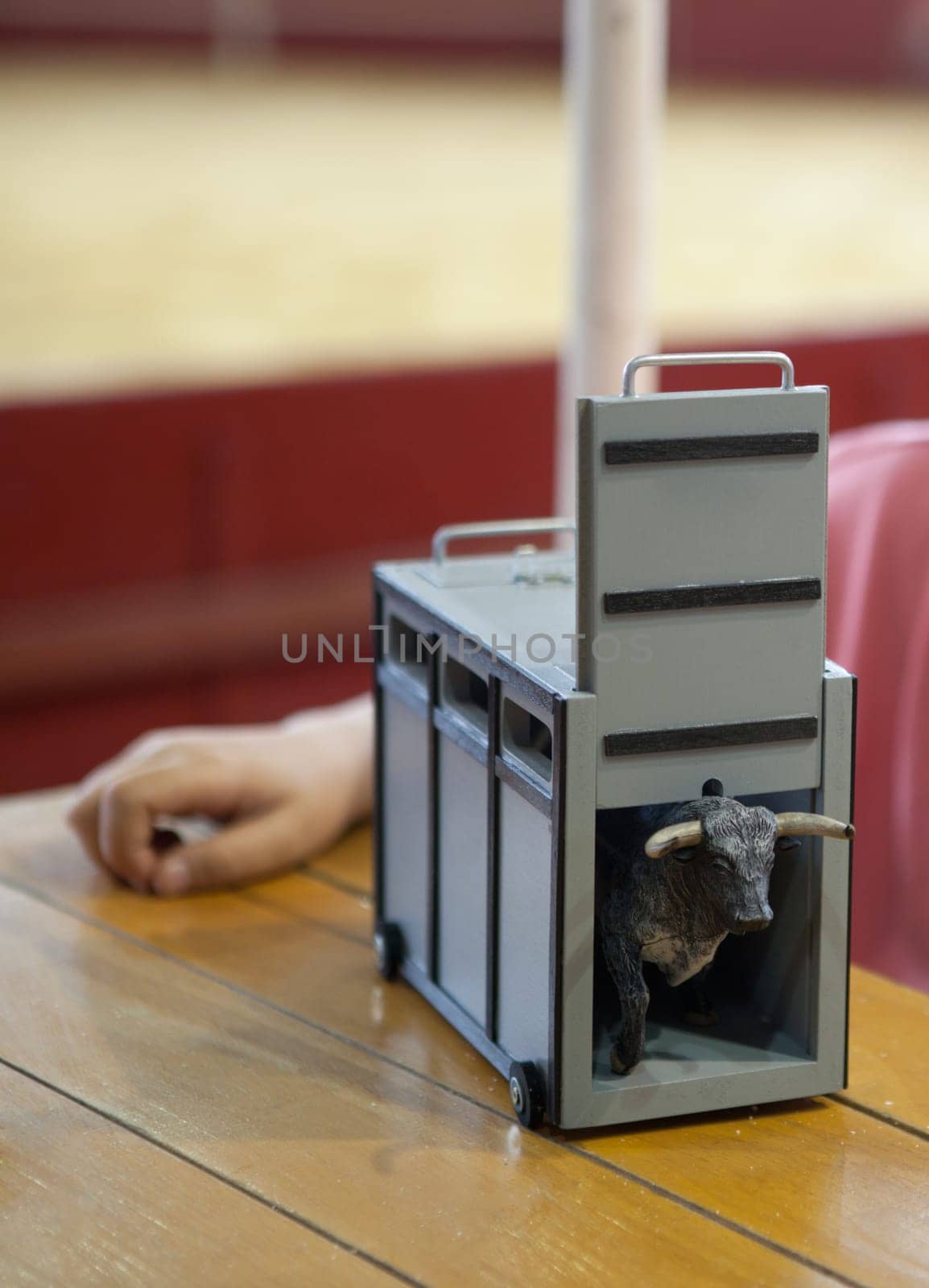 Child playing with a transport box for fighting bull toy over a wooden table