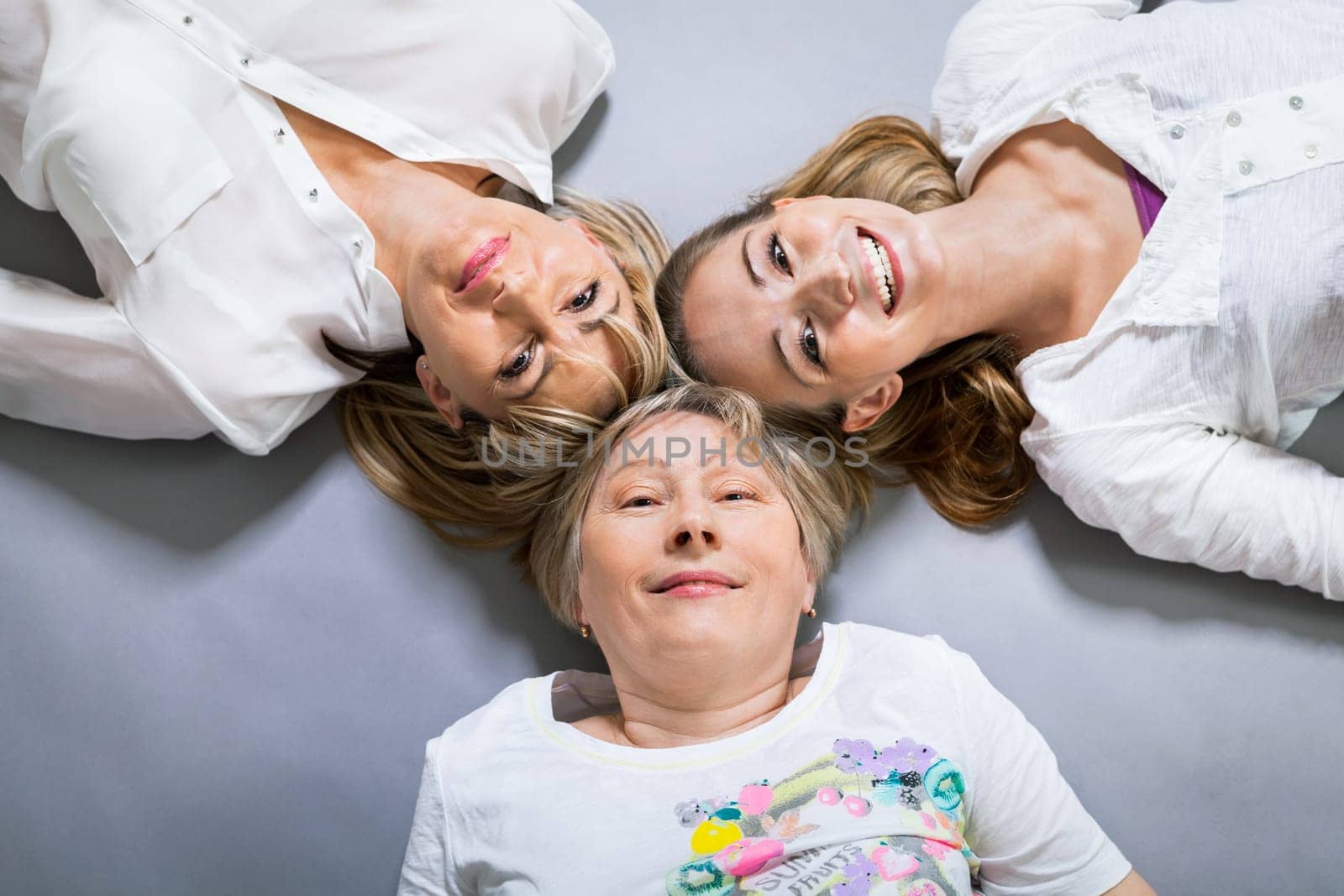 three generations grandmother mother and daughter in portrait against grey background family
