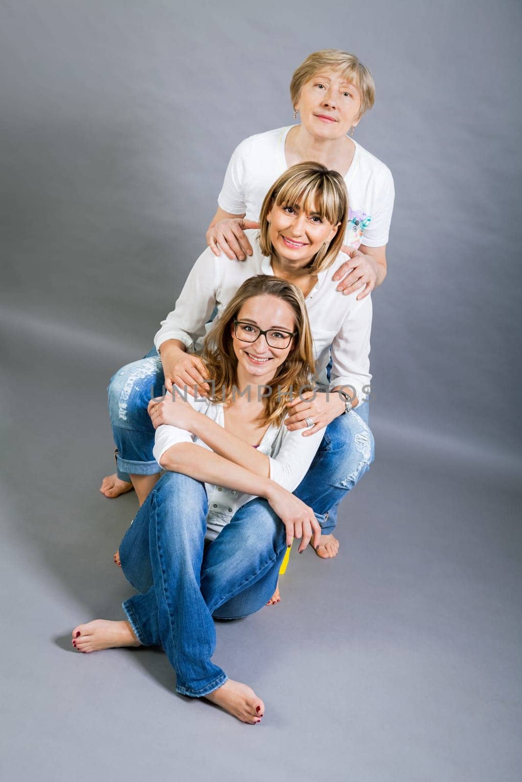 three generations grandmother mother and daughter in portrait against grey background family