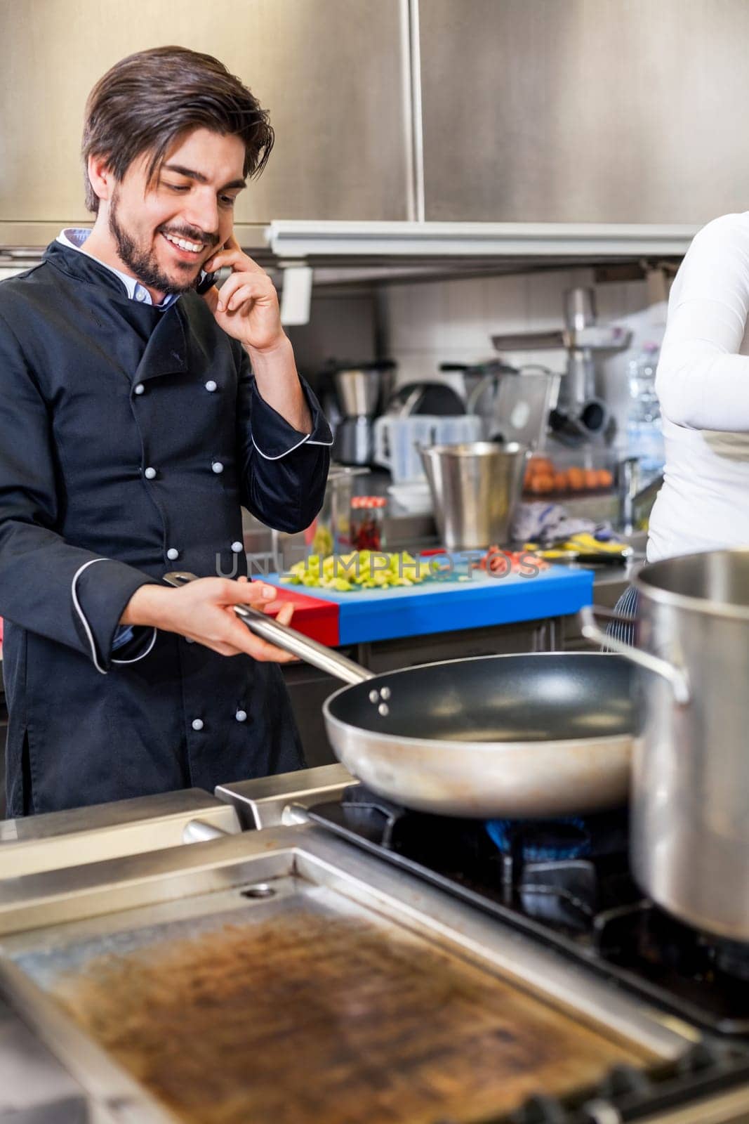 young chef on the phone while cooking in the restaurant kitchen work success stress communication
