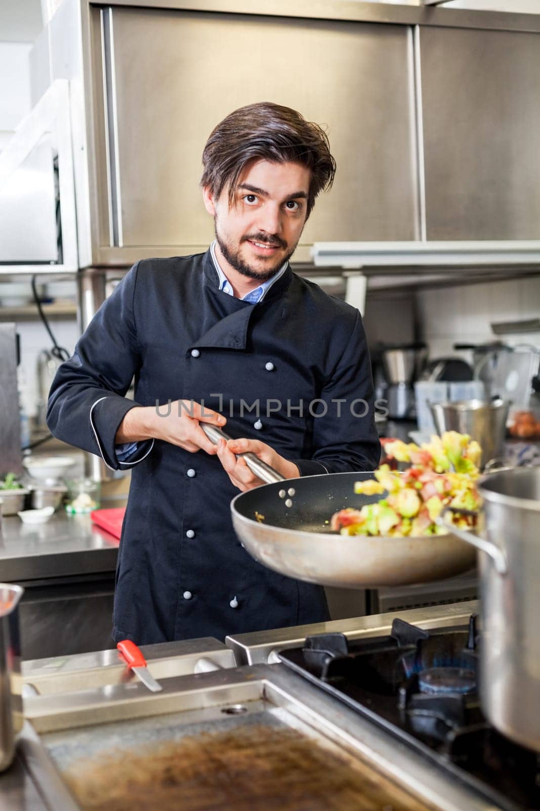 young adult chef in the restaurant kitchen while cooking at the herd preparation