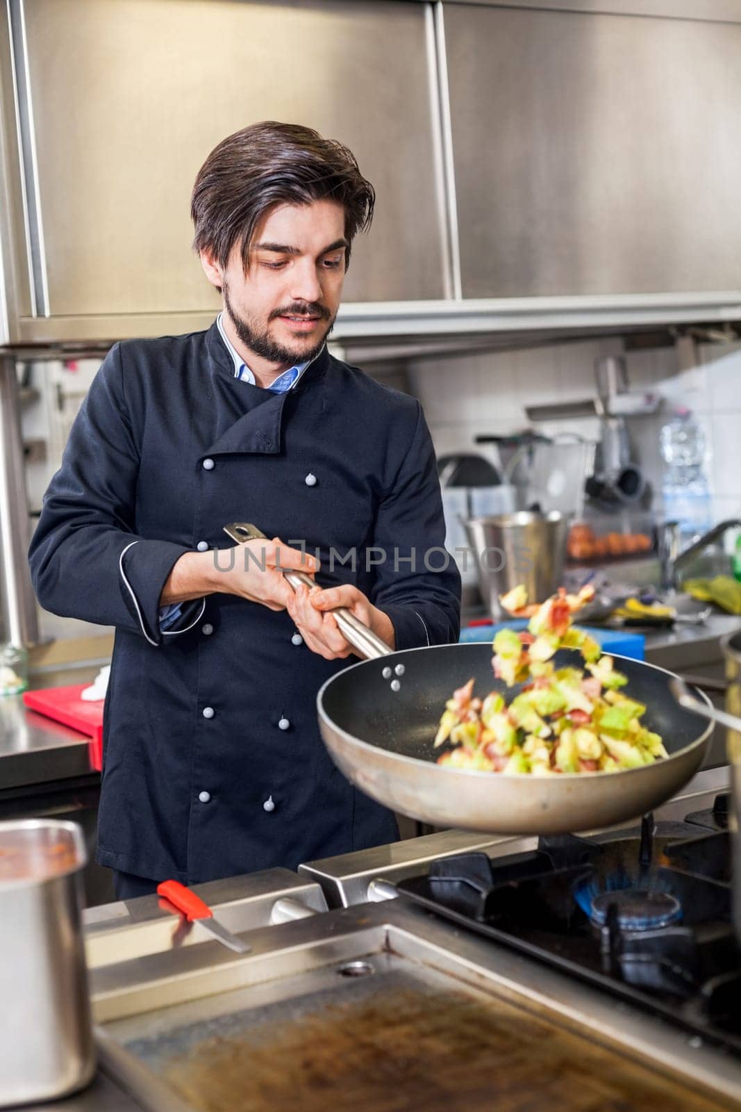 young adult chef in the restaurant kitchen while cooking at the herd preparation