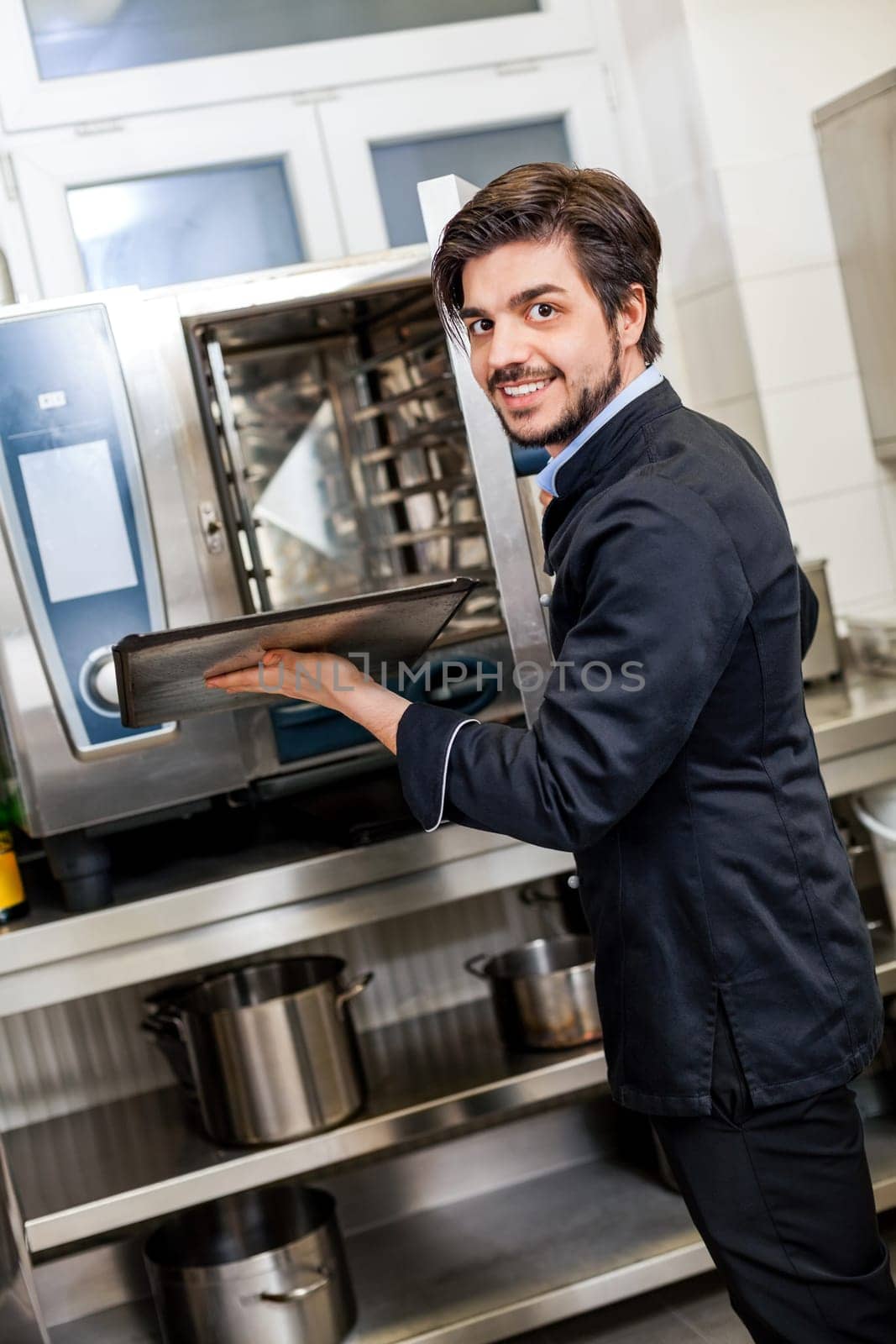 young adult chef in the restaurant kitchen while cooking at the herd preparation