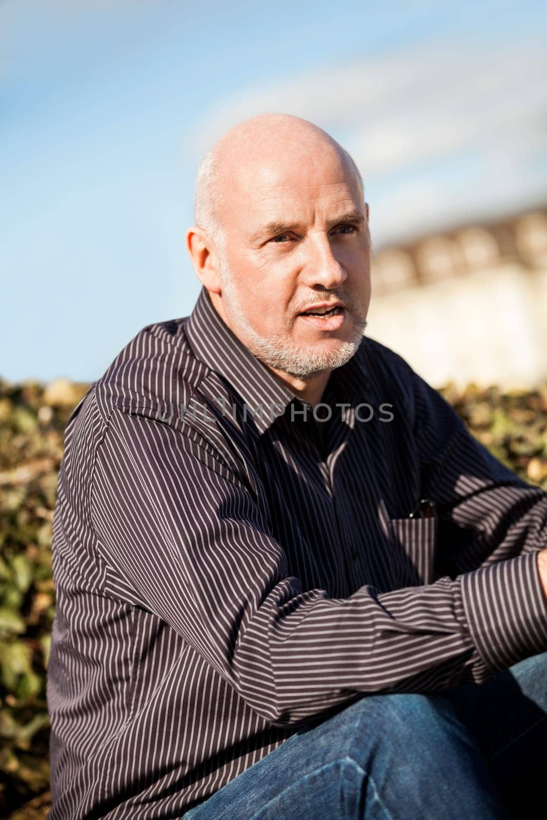 Trendy senior man with sporty clothes relaxes in the outdoors in the sun
